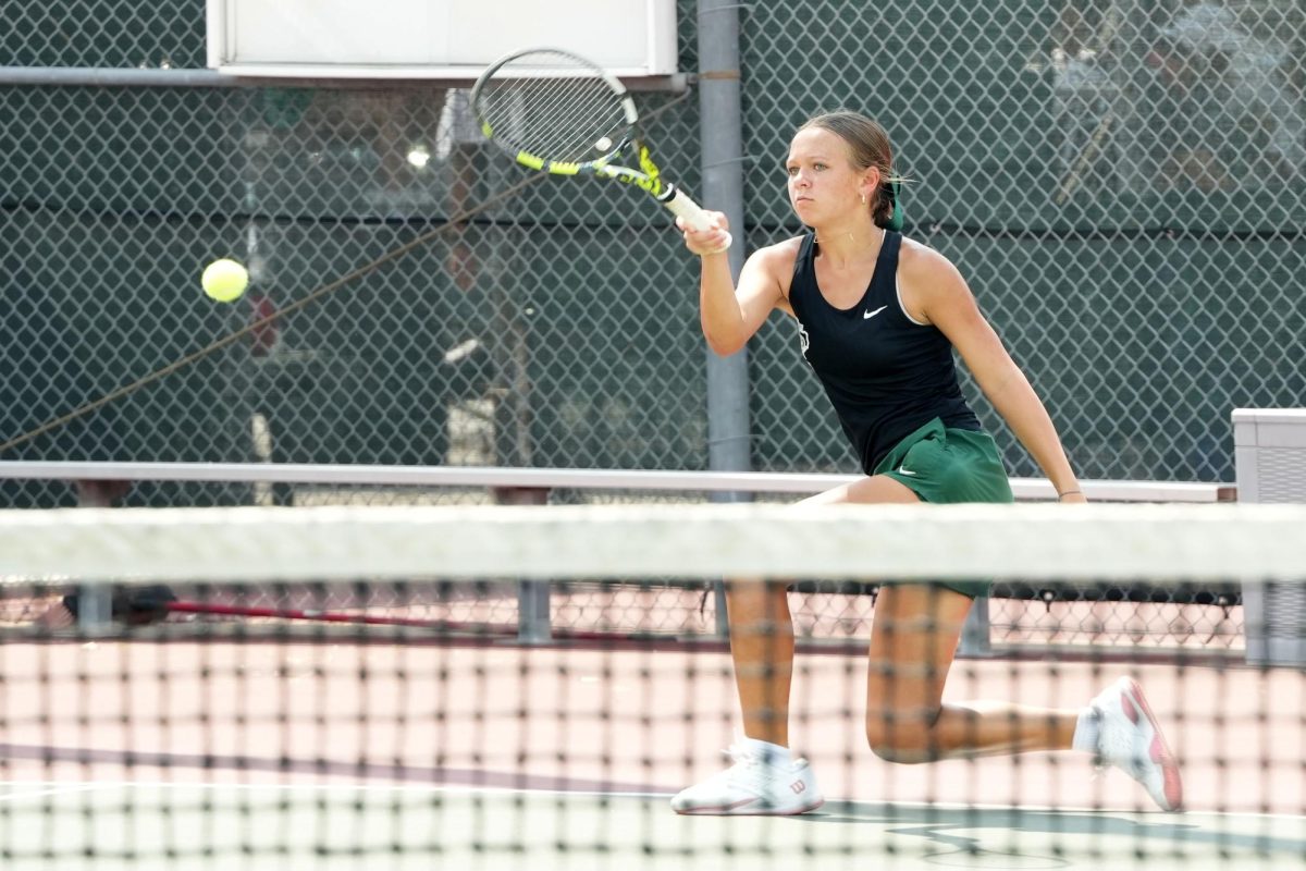 After hitting the ball, sophomore Reagan Sharpe watches as the ball passes over the net in a match against Magnolia on Aug. 8. 