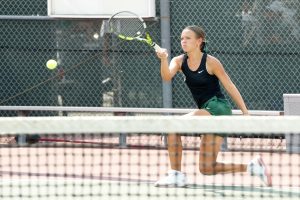 After hitting the ball, sophomore Reagan Sharpe watches as the ball passes over the net in a match against Magnolia on Aug. 8. 