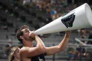 During a football game against Dayton on Sept. 5, senior Alec Krippel yells into a megaphone while cheering on the sideline. Krippel has been a part of the coed cheer team for two years.