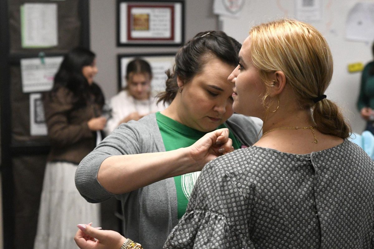 Theater director Brandi Perkins removes the boning from senior Emerson Harris's costume during seventh period on Sept. 3. 