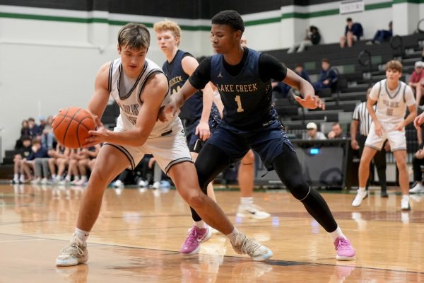 During a game against Lake Creek, junior Trey Nicholds dribbles the ball into a defender before making a layup. The Panthers lost the game, 60-58, on Nov. 25. 