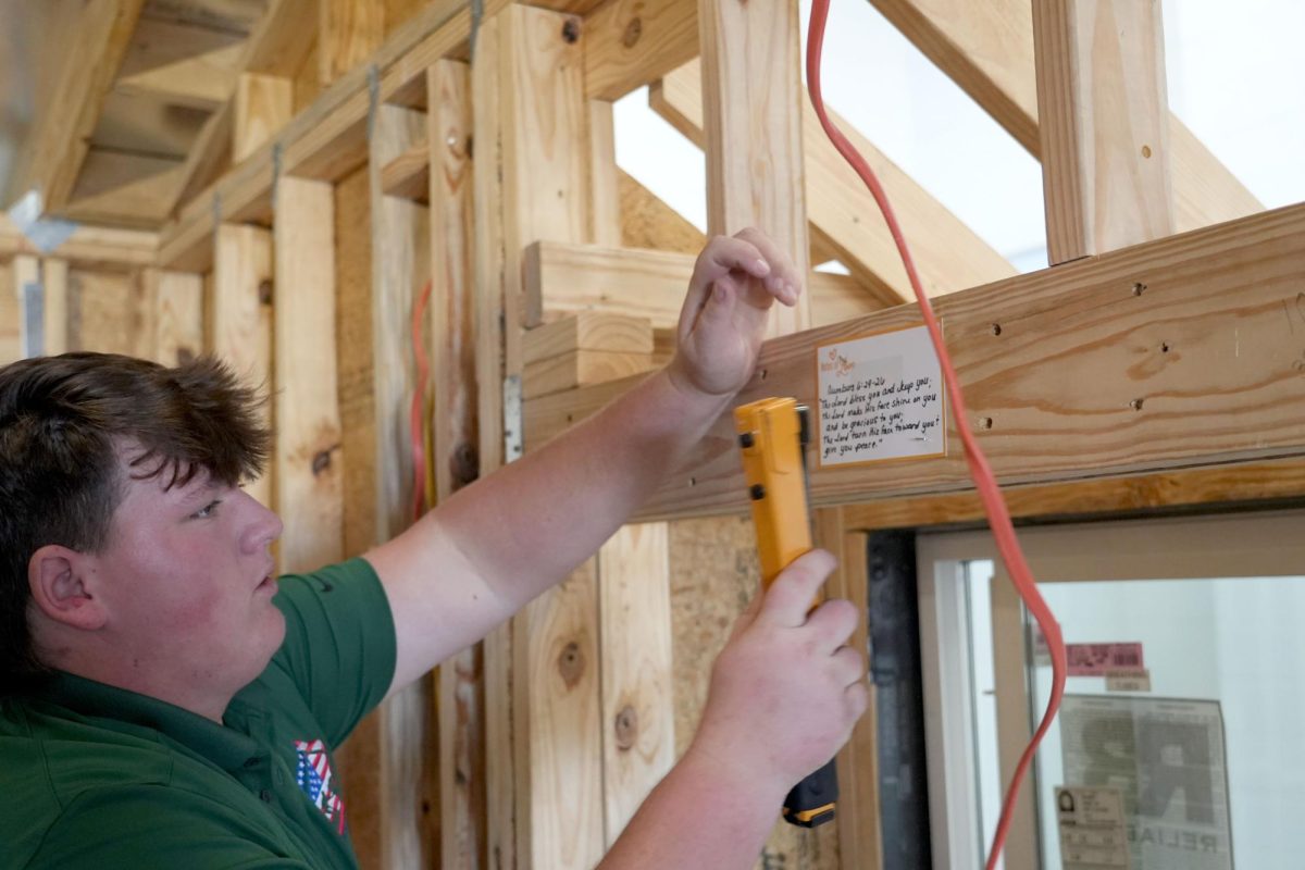 Senior Austin Whittington staples "Notes of Love" to the structure of the latest Tiny Home. 