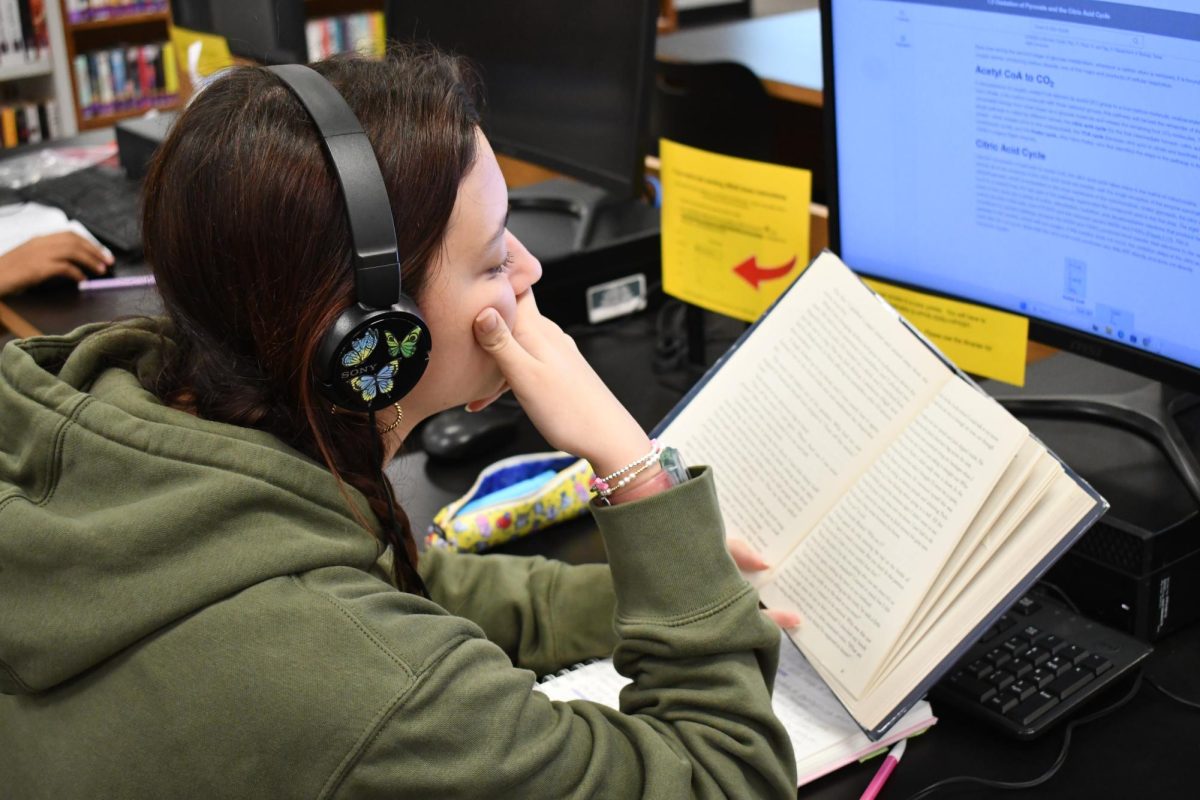 Senior Sarah Orth reads a novel during her library aide period.
