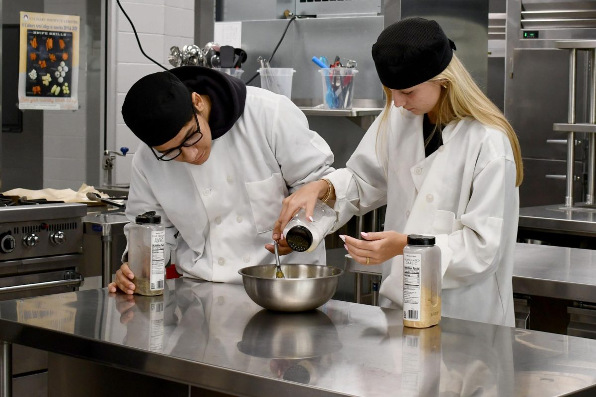 Senior Cesar Delgado and sophomore Avery Jones whisk eggs and measure salt to whisk into the eggs during culinary class earlier this year.