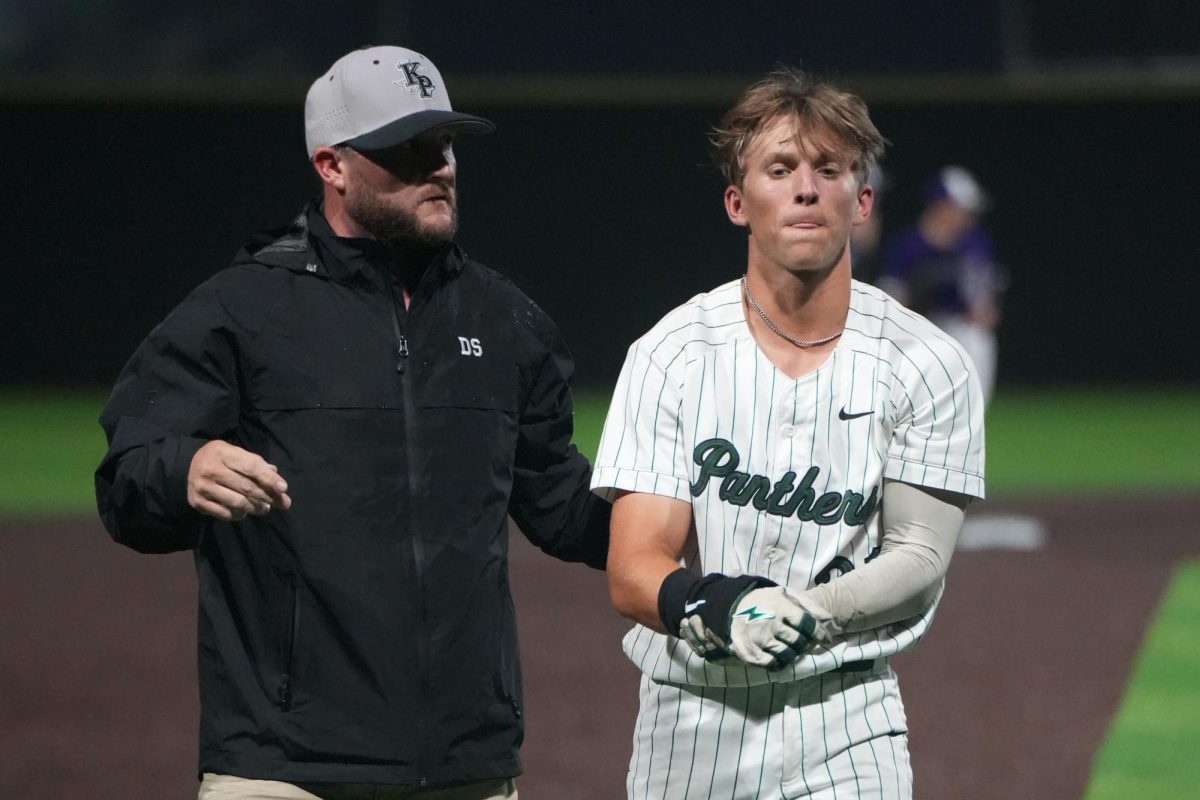 Head athletic trainer Daniel Scalia helps senior Logan Bear off the field after dislocating his shoulder diving into third base against Dayton on Feb. 10. Earlier in the game, he broke the single season stolen base record with 27. 