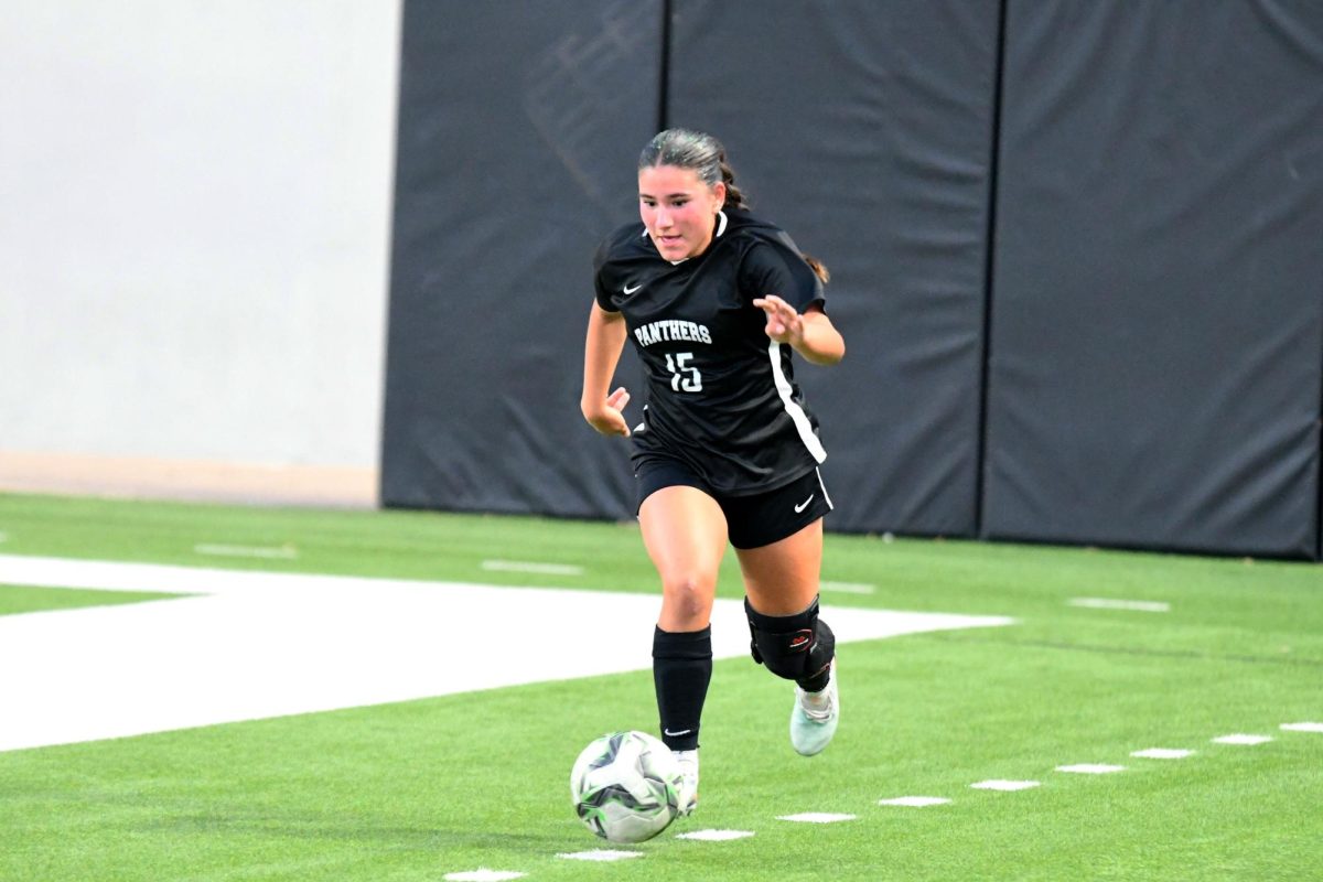 Junior Isa Price looks down at the ball, while dribbling it up the field. 