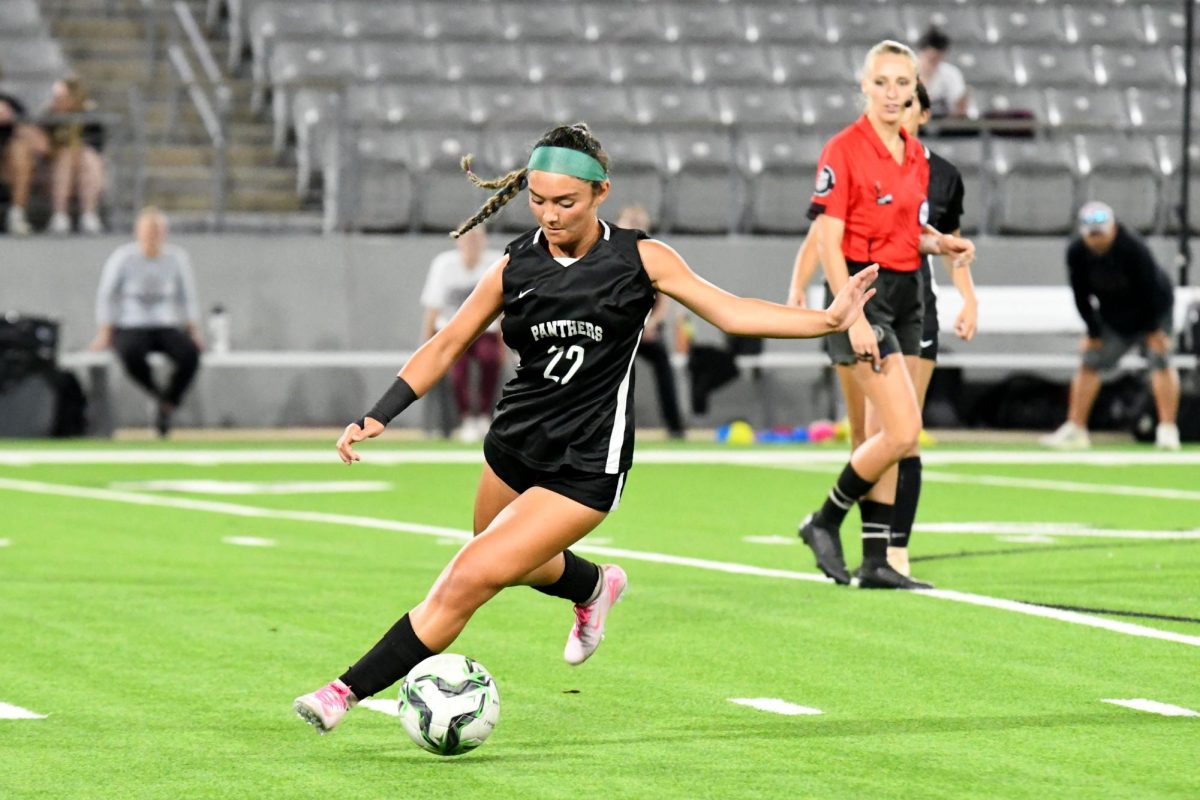 In the middle of the field, sophomore Liani Villegas looks down while making an attempt to pass the ball to one of her teammates. 