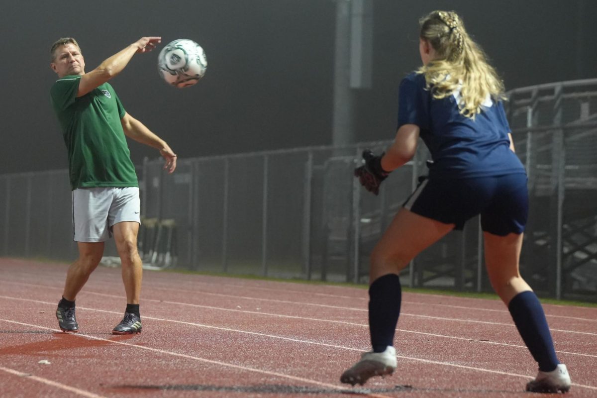 Assistant soccer coach Luke Gorney warms up freshman goalkeeper Chloe Inman during the varsity game against MacArthur on Jan. 21.
