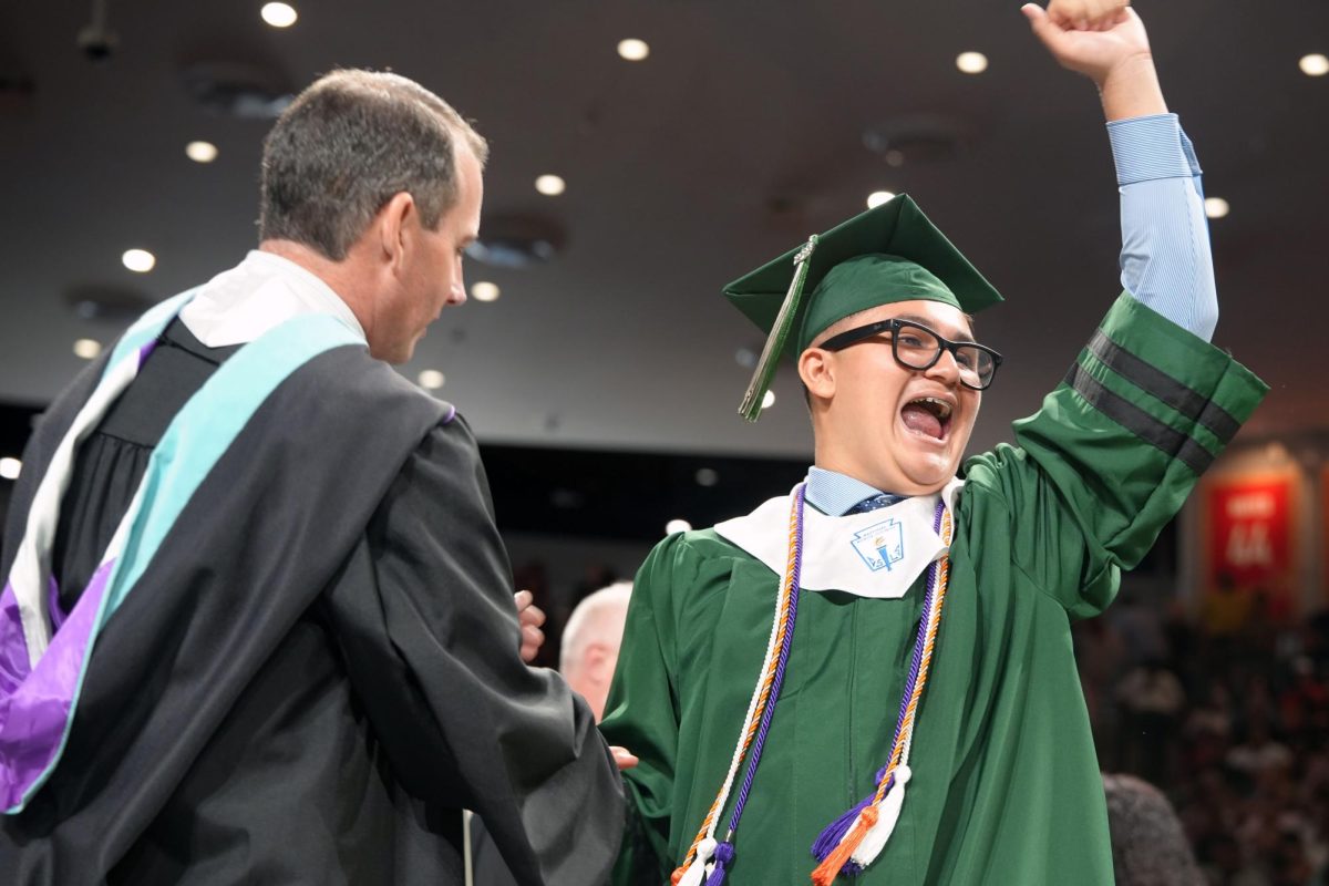 Senior Jesse Ramirez waves to the crowd as he shakes principal Wes Solomon's hand during the graduation ceremony on May 24. 