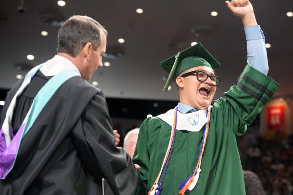 Senior Jesse Ramirez waves to the crowd as he shakes principal Wes Solomon's hand during the graduation ceremony on May 24. 