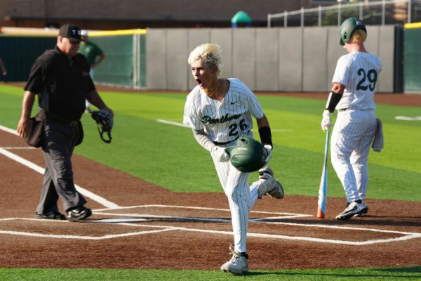 After hitting a homerun, senior Dylhan Bodkin celebrates towards the dugout after reaching home plate.